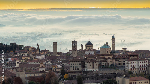 Bergamo, Italy. Amazing landscape of the town covered by the fog arising from the plain. Fall season. Morning. Sunrise time