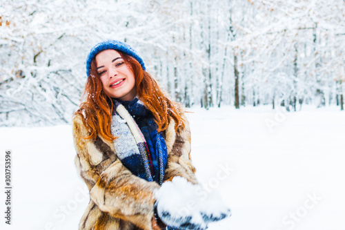 young beautiful woman playing with snow in winter forest