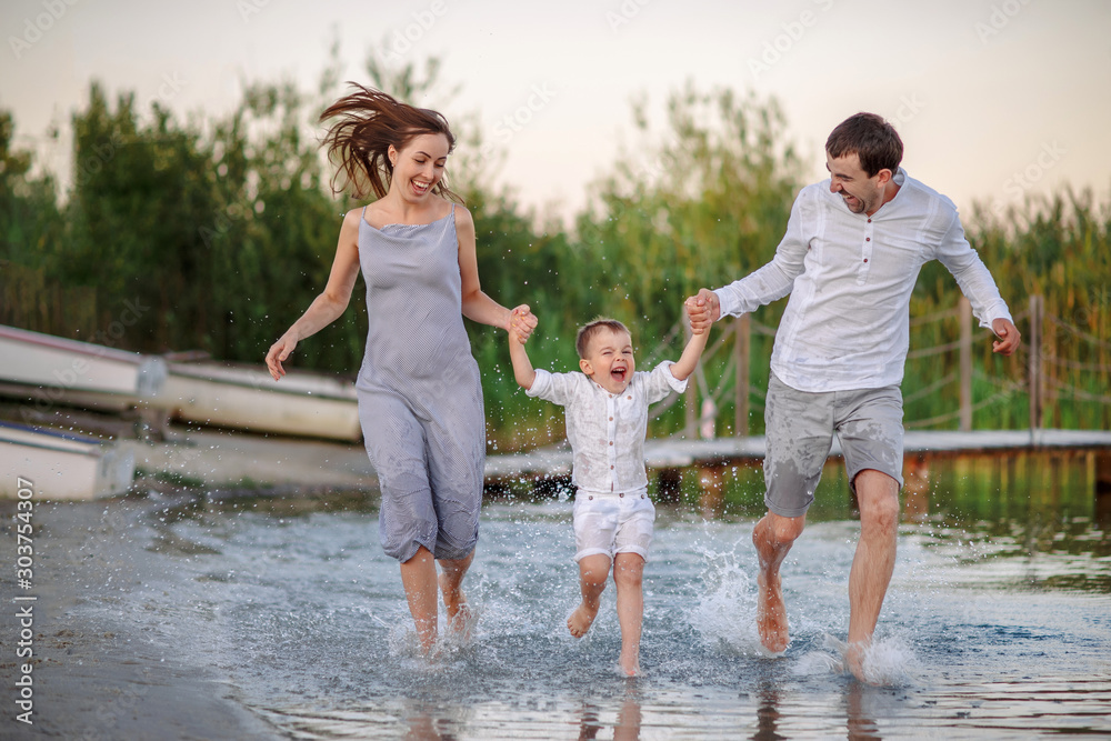 Happy young family having fun running on water at the beach. Travel lifestyle, parents with kids on summer vacation Happy young family having fun running on water at the beach. Travel lifestyle, parents with kids on summer vacation