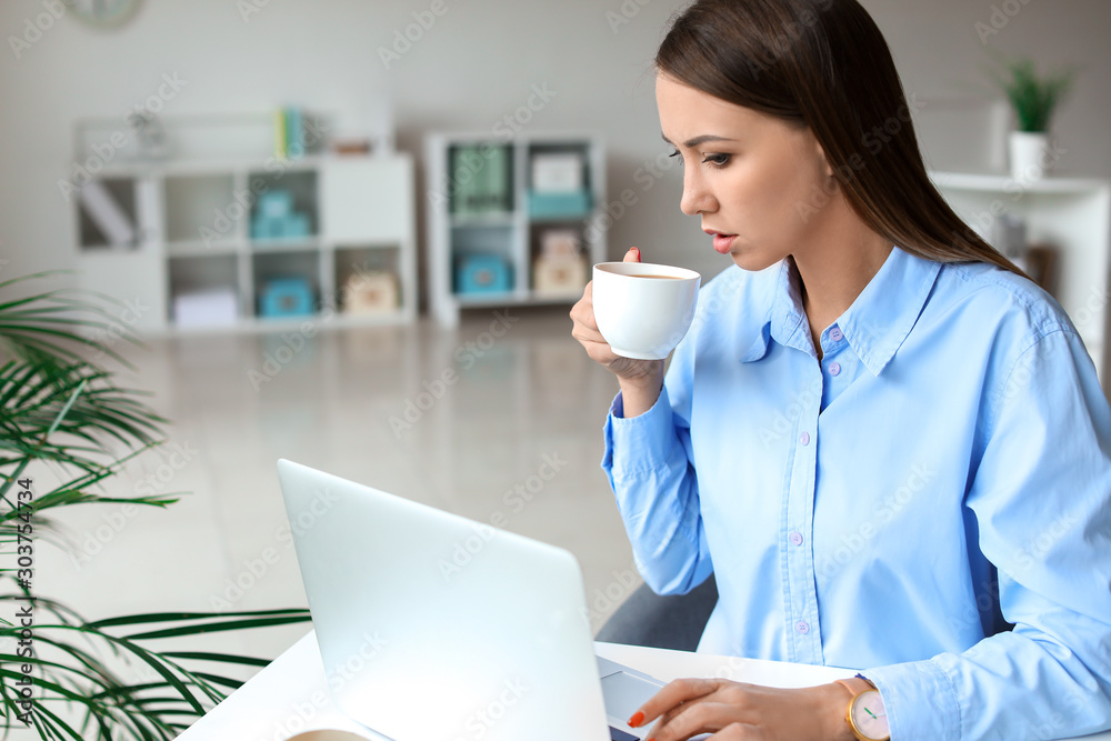 Young woman drinking coffee while working in office Young woman drinking coffee while working in office