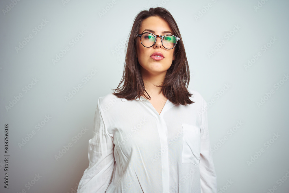 Young beautiful business woman wearing glasses over isolated background with serious expression on face. Simple and natural looking at the camera.
