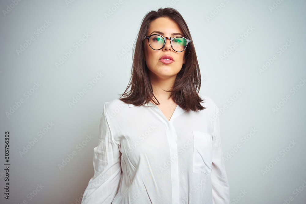 Young beautiful business woman wearing glasses over isolated background with serious expression on face. Simple and natural looking at the camera. Young beautiful business woman wearing glasses over isolated background with serious expression on face. Simple and natural looking at the camera.