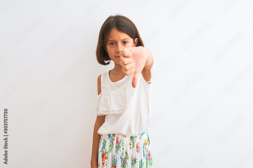 Young beautiful child girl wearing casual dress standing over isolated white background looking unhappy and angry showing rejection and negative with thumbs down gesture. Bad expression. Young beautiful child girl wearing casual dress standing over isolated white background looking unhappy and angry showing rejection and negative with thumbs down gesture. Bad expression.