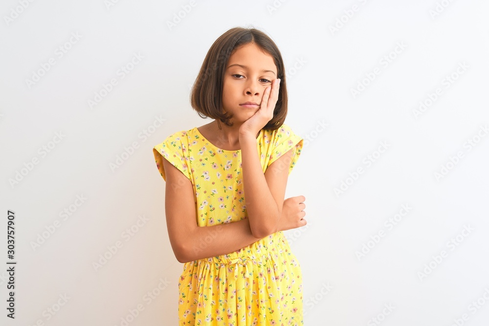 Young beautiful child girl wearing yellow floral dress standing over isolated white background thinking looking tired and bored with depression problems with crossed arms. Young beautiful child girl wearing yellow floral dress standing over isolated white background thinking looking tired and bored with depression problems with crossed arms.