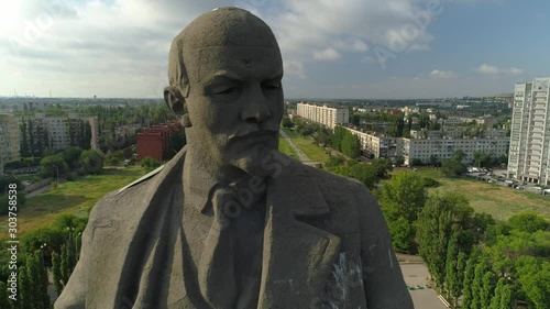 Flight close up face concrete epic monument Lenin Volgograd socialist communist landmark. Typical city Russia central square historical cityscape. Soviet and modern houses. Summer blue sky clouds