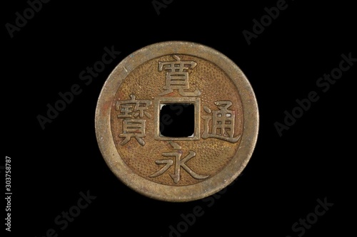 A close up image of a bronze, Chinese cash coins, shot close up in macro against a black background