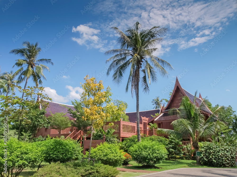 View of Thai houses around with green garden and blue sky background, King Rama II Memorial Park, Amphawa District, Samut Songkhram, Thailand.