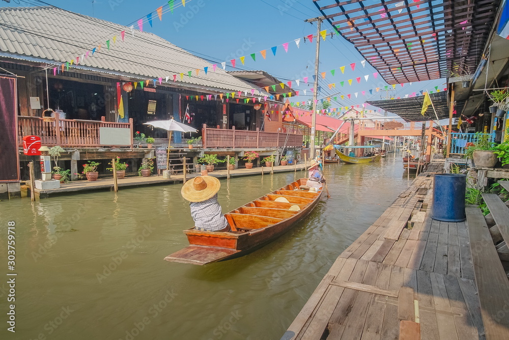view of a gardener rowing small boat in canal, Damnoen Saduak Floating Market, Ratchaburi, Thailand.