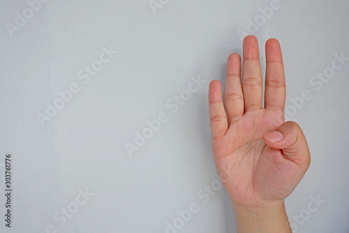 Close-up of female hand showing four fingers isolated on grey background. Side view close up details.