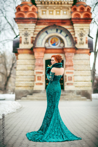 red-haired girl in a long green dress with a train in a historical artistic image