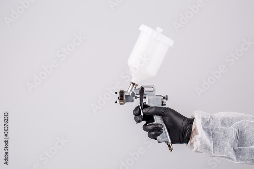 Obraz na plátně Hand and spray gun at work on white background