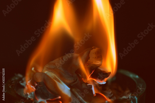 Fotografie Crumpled piece of paper burns out in a glass ashtray
