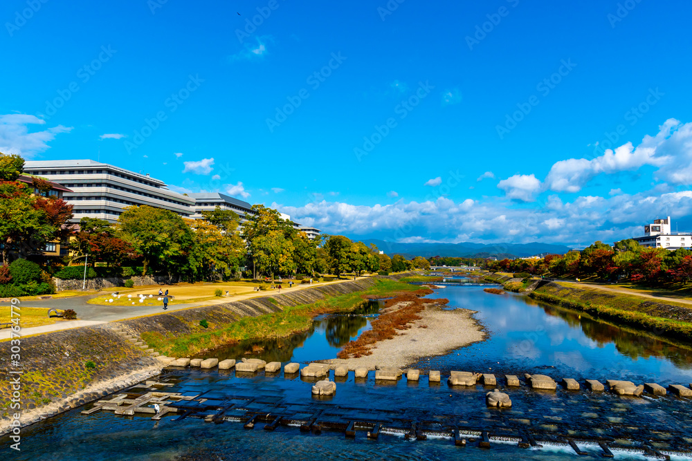 People relax by Kamo river in Kyoto, Japan in autumn season with  Autumn leaves.