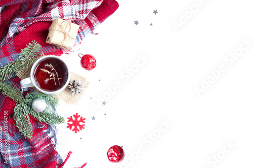 Hot christmas beverage black tea in mug with new year decorations, Cone, present, silver ball, apple, fir tree, plaid on white. Winter time top view.