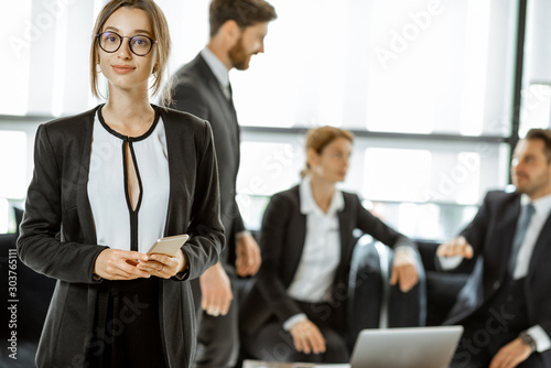 Portrait of a beautiful white collar busines woman standing in front of business team at the luxurious office photo