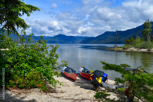 Fototapeta Naklejka Na Ścianę i Meble -  Two canoes on the shore of Murtle Lake, Canadian Wilderness, pfd vest, ready to sail. Beautiful mountain lake and sunny day, bushes, green leaves