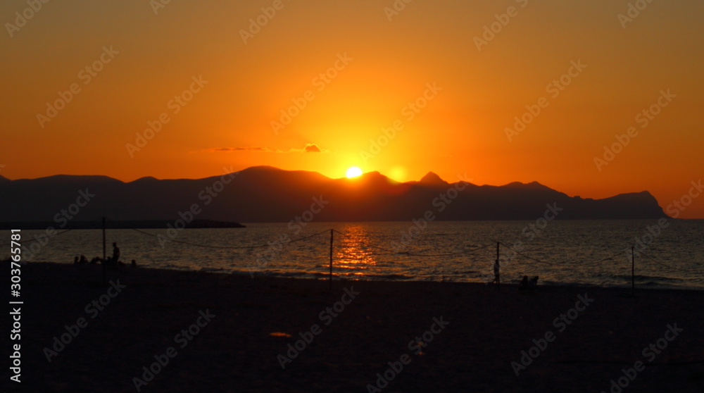evocative immagine of sunset over the sea with promontory in the background