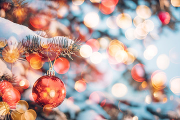 Christmas ball on a Christmas tree on the street. Winter snowy background with lens flare bokeh highlights