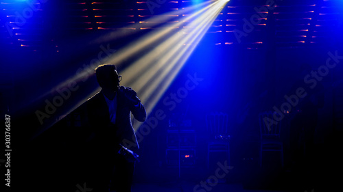 close up photo the silhouette of a singer in dark concert spotlights