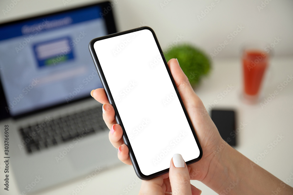 female hands holding phone with isolated screen over laptop female hands holding phone with isolated screen over laptop