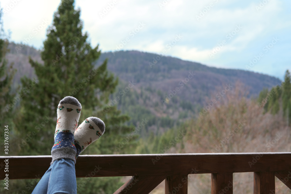 Φωτογραφία The young woman's feet laid on the wooden railing on the background of the mountains
