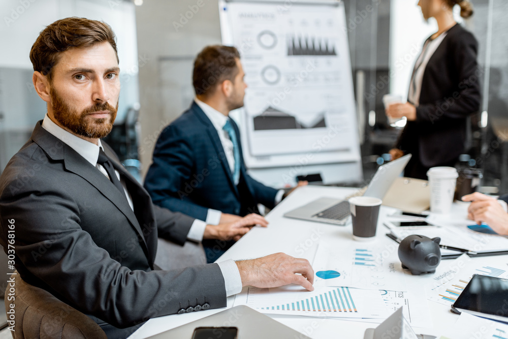Portrait of a handsome business man sitting during a conference with employees in the meeting room Portrait of a handsome business man sitting during a conference with employees in the meeting room
