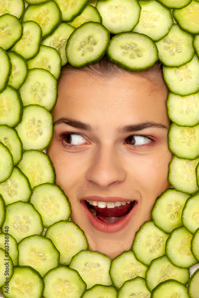 Φωτογραφία Young beautiful happy woman posing with slices of cucumber around her face