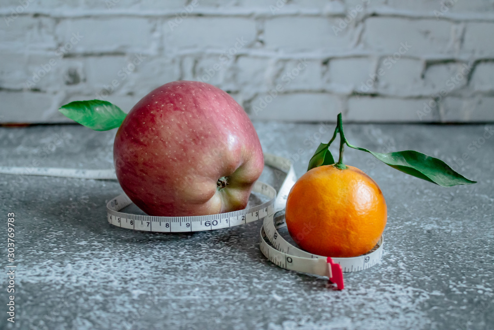 Red apple and orange for weight loss while dieting, centimeter measuring tape Red apple and orange for weight loss while dieting, centimeter measuring tape