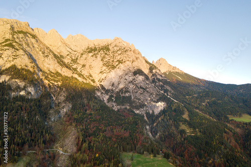 Aerial view of majestic european Alps mountains covered in evergreen pine forest in autumn.