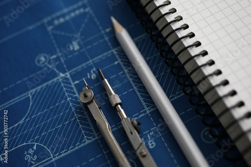 Pair of compasses and white pencil lying over blueprint paper © megaflopp