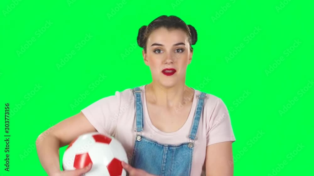 Girl with football ball, cheers for his favorite team while watching the match on green screen at studio, slow motion. Girl with football ball, cheers for his favorite team while watching the match on green screen at studio, slow motion.