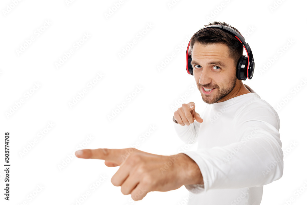 Fototapeta premium handsome young man in headphones listening to music and points hand at you, isolated on white background.