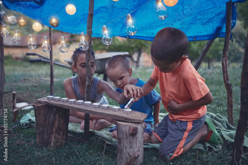 Kids making a small tent with candles and lampions in the backyard.