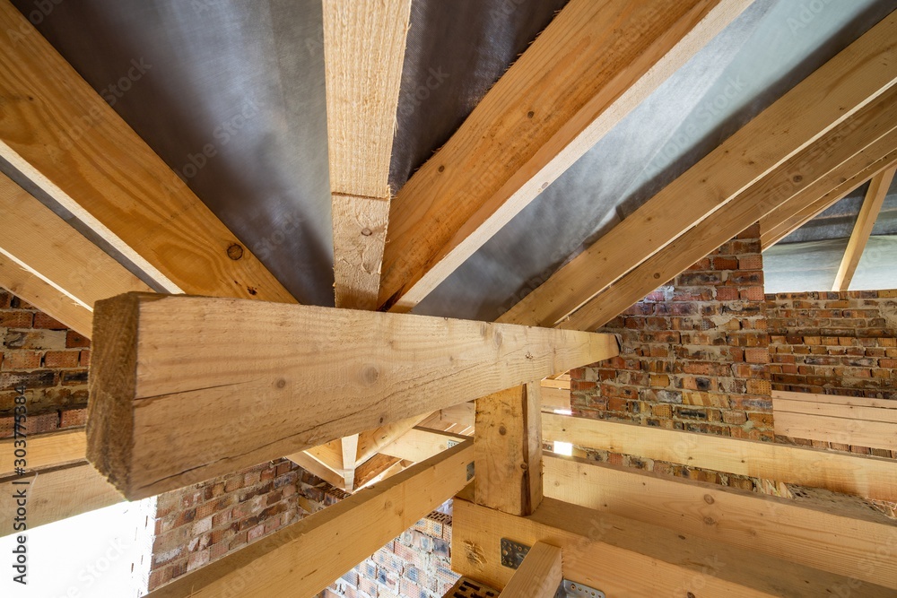 Attic of a building under construction with wooden beams of a roof structure and brick walls. Attic of a building under construction with wooden beams of a roof structure and brick walls.
