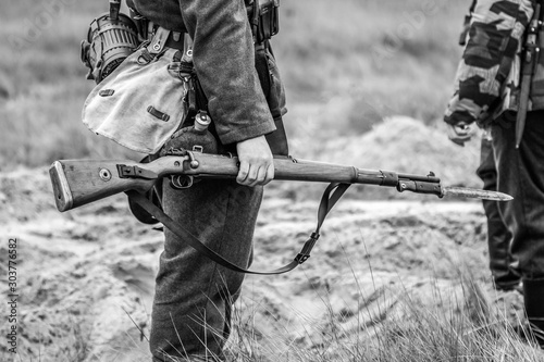 A rifle with a bayonet with a knife in the hands of a Wehrmacht soldier from World War II. Black and white photography photo