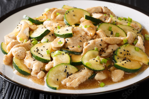 Tasty stewed chicken fillet with zucchini in spicy sauce close-up on a plate. horizontal