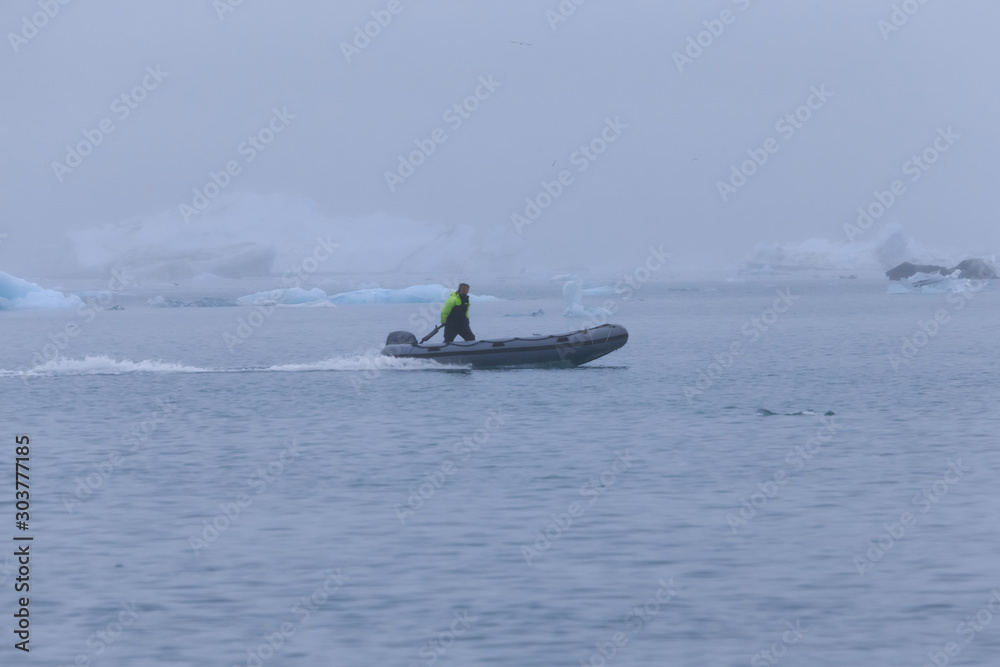 Fototapeta premium Man on a boat between bizarre ice floes of Iceberg lagoon jokulsarlon on the south of Iceland