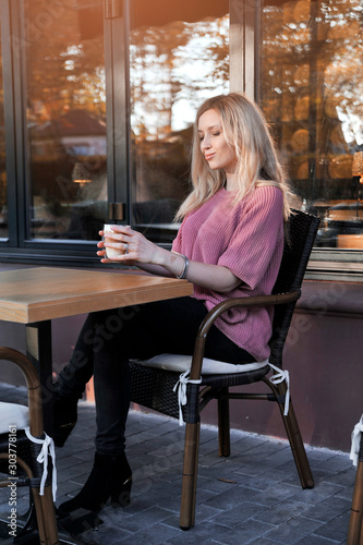 Beautiful woman drinks cappiccino at sunset outdoors. © Alona