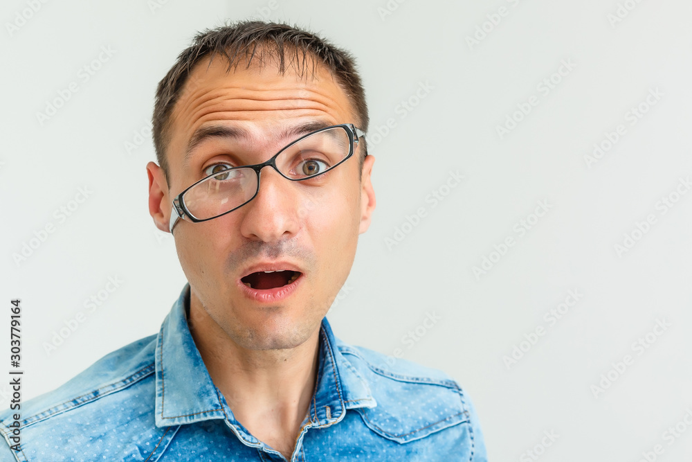 A goofy man wearing trendy nerd glasses isolated over white with a funny expression on his face.