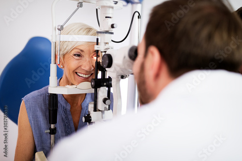 Optometrist examining senior woman in modern ophthalmology clinic photo