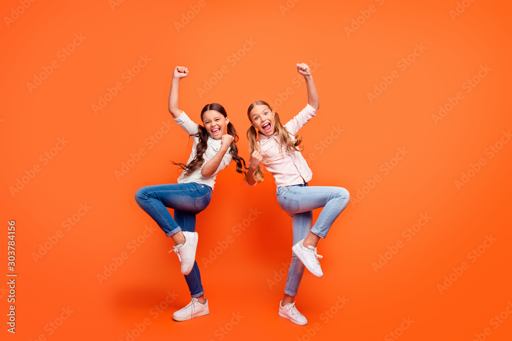 Full size photo of delighted expression crazy funky two girlfriends celebrate competition win scream yeah raise fists wear casual style outfit isolated orange color background Full size photo of delighted expression crazy funky two girlfriends celebrate competition win scream yeah raise fists wear casual style outfit isolated orange color background