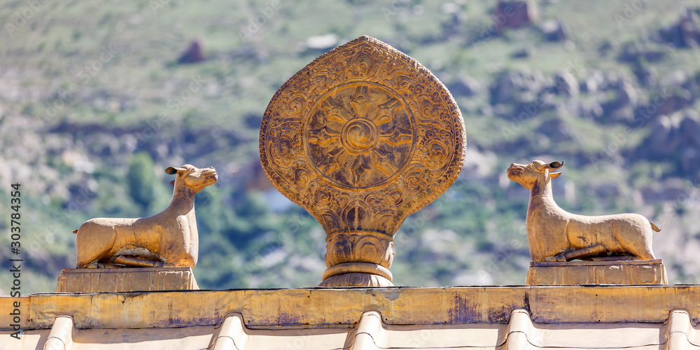 Φωτογραφία LHASA, TIBET / CHINA - July 31, 2017: Golden colored dharma wheel and deers on the roof top of Sera Monastery