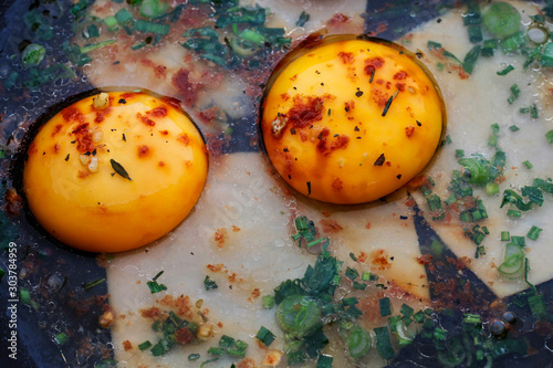 Consecutive steps of preparing fried eggs with ham and herbs