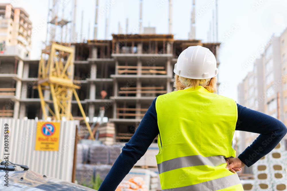 A female builder worker at a construction site works and controls the process. A female builder worker at a construction site works and controls the process.