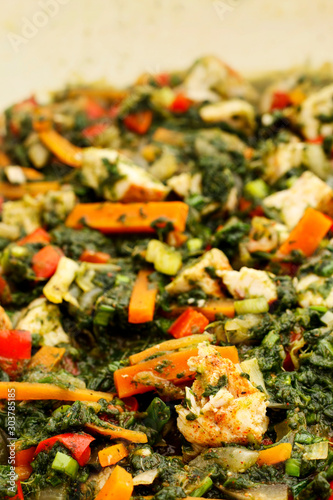 Chicken with vegetables and spinach in a pan.