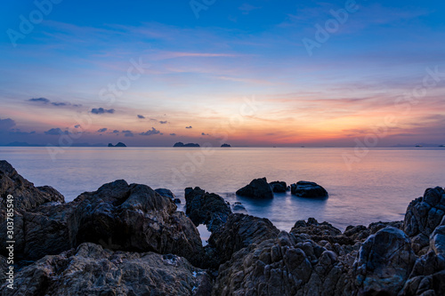 Spectacular sunset sky over sea and rocky beach on a tropical island