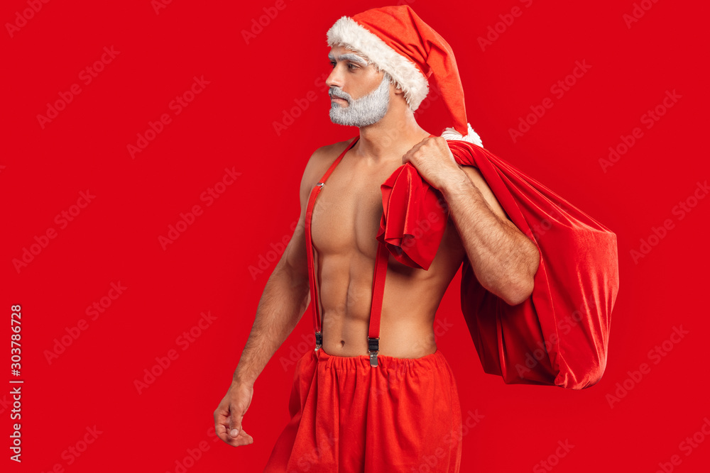 Φωτογραφία Adult shirtless Santa Claus holding sack full of presents, looking away