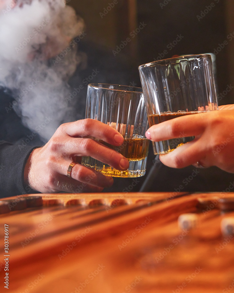 People drinking whiskey, smoking hookah and playing backgammon.