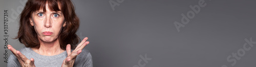 frustated middle aged woman expressing hopelessness, grey long banner photo