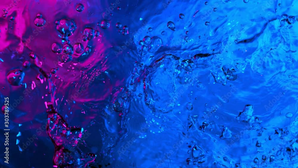 Super slow motion of splashing water illuminated by neon lights. Filmed on very high speed camera, 1000 fps.